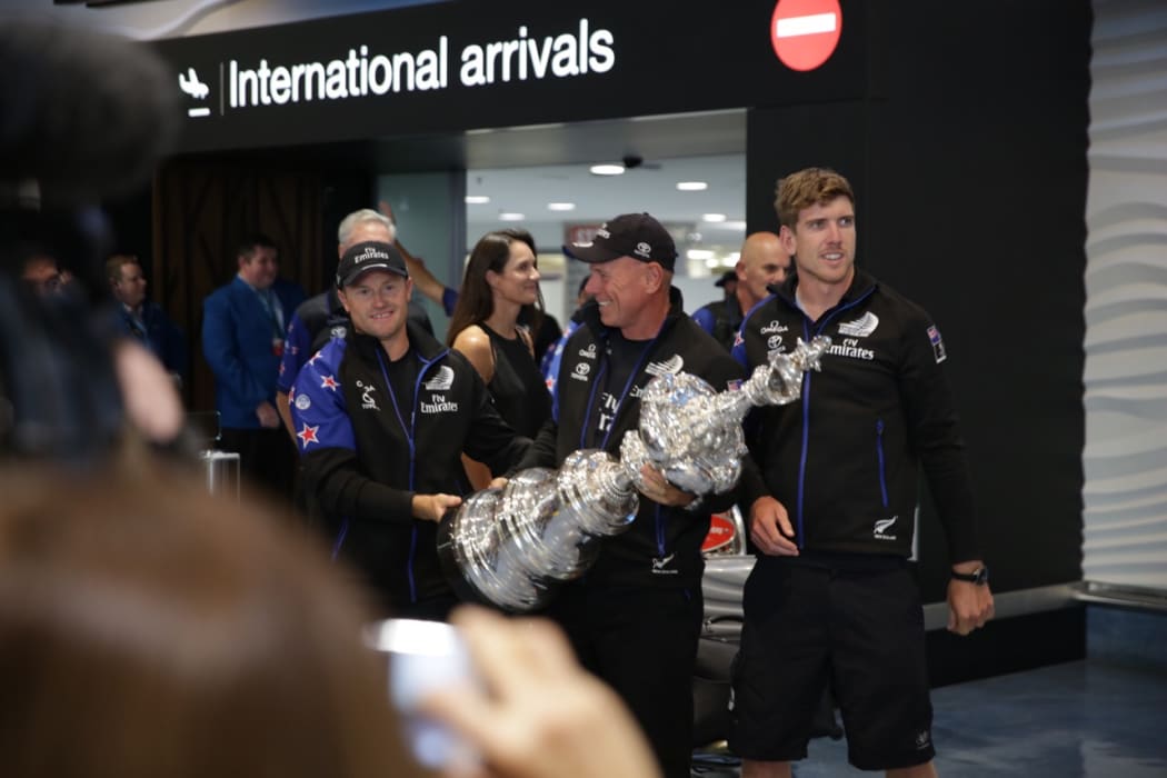 Team NZ crew members, from left, Glenn Ashby, Peter Dalton and Peter Burling, bringing the America's Cup trophy home.