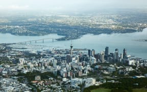 An aerial view of Auckland city, showing both the Harbour Bridge and the Sky Tower.