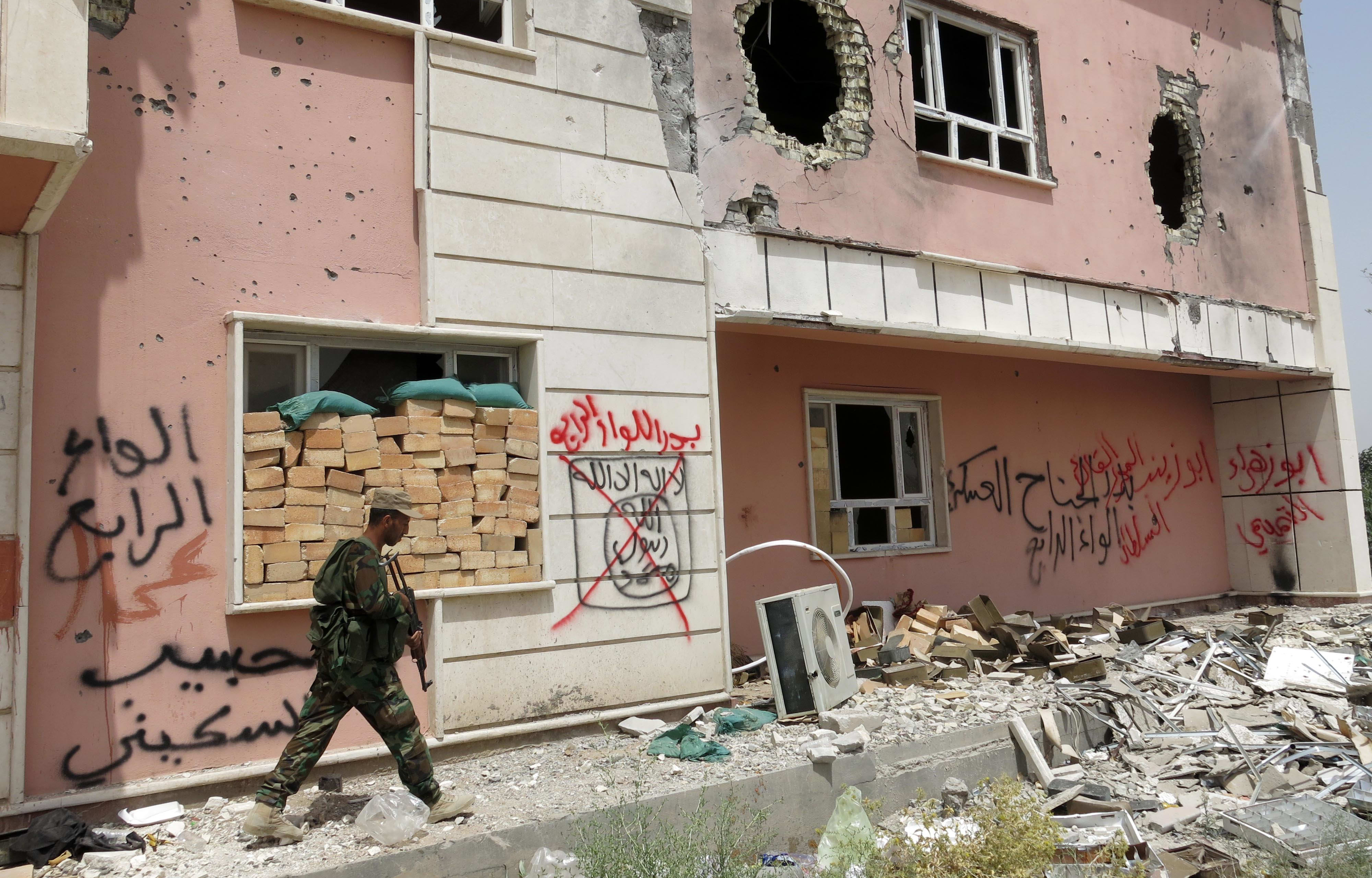 A fighter from a Shiite paramilitary units, known as Hashd Shaabi, walks near a damaged building in Harariyat village on the outskirts of Fallujah.