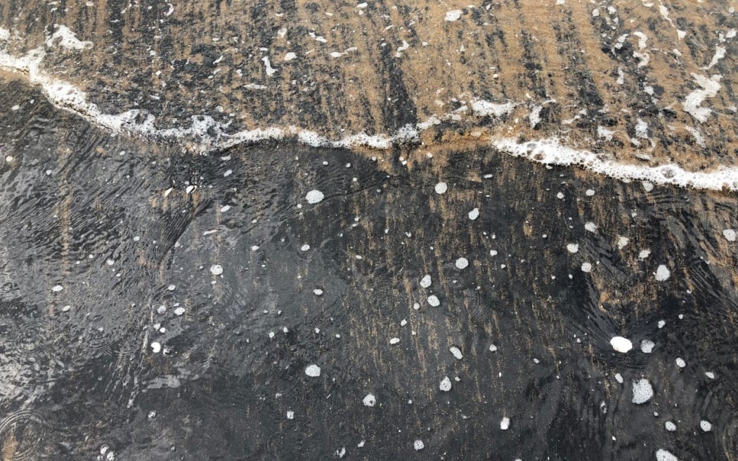 Black sand at low tide.
