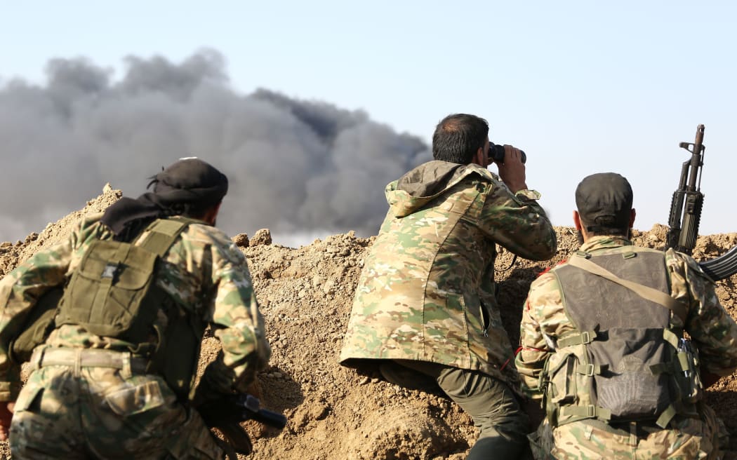 Turkish-backed Syrian rebels watch the border town of Ras al-Ain on October 12, 2019, during their assault on Kurdish-held border towns in northeastern Syria.