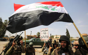 Members of the Iraqi federal police wave national flags during a parade in the Old City of Mosul on 2 July 2017.