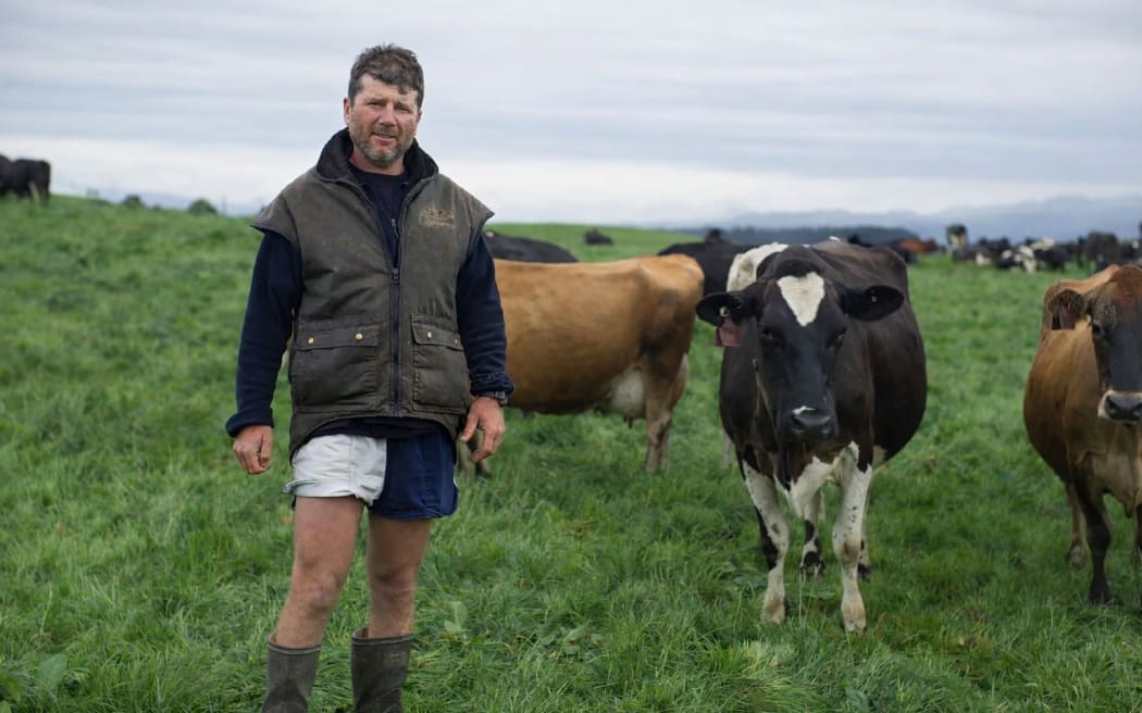 North Otago farmer Tim Richards stands in a field beside some of his cows
