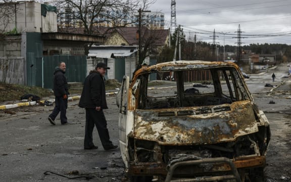 People walk through a street strewn with several dead bodies in Bucha, northwest of Kyiv.