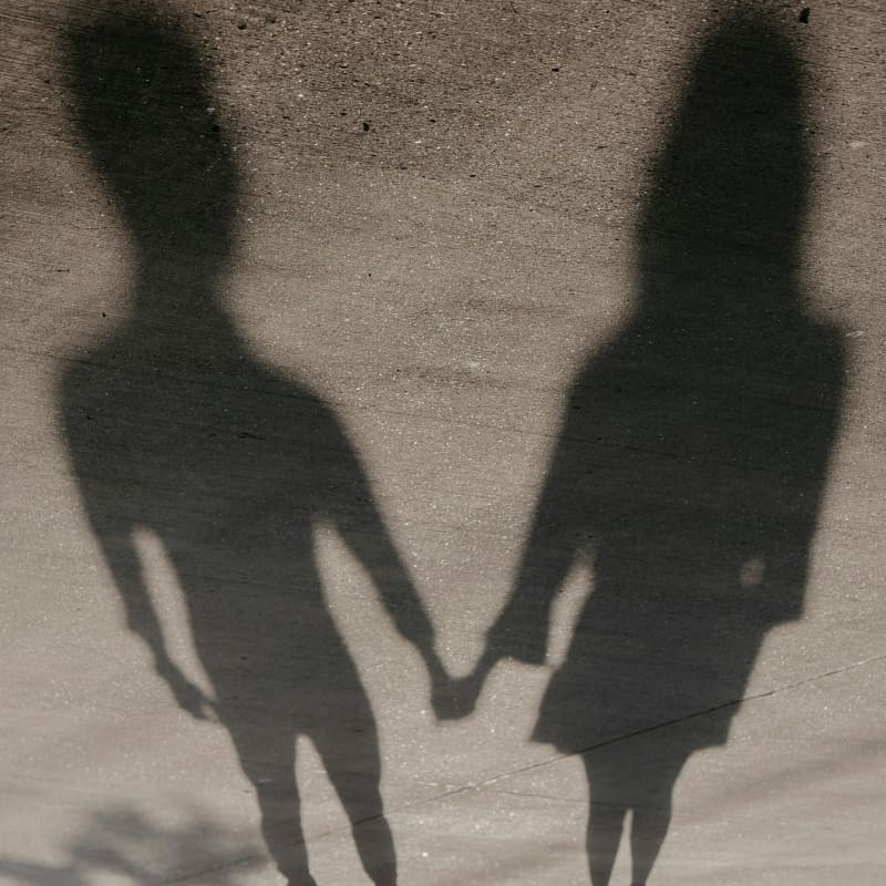 The shadows of two people hold hands.