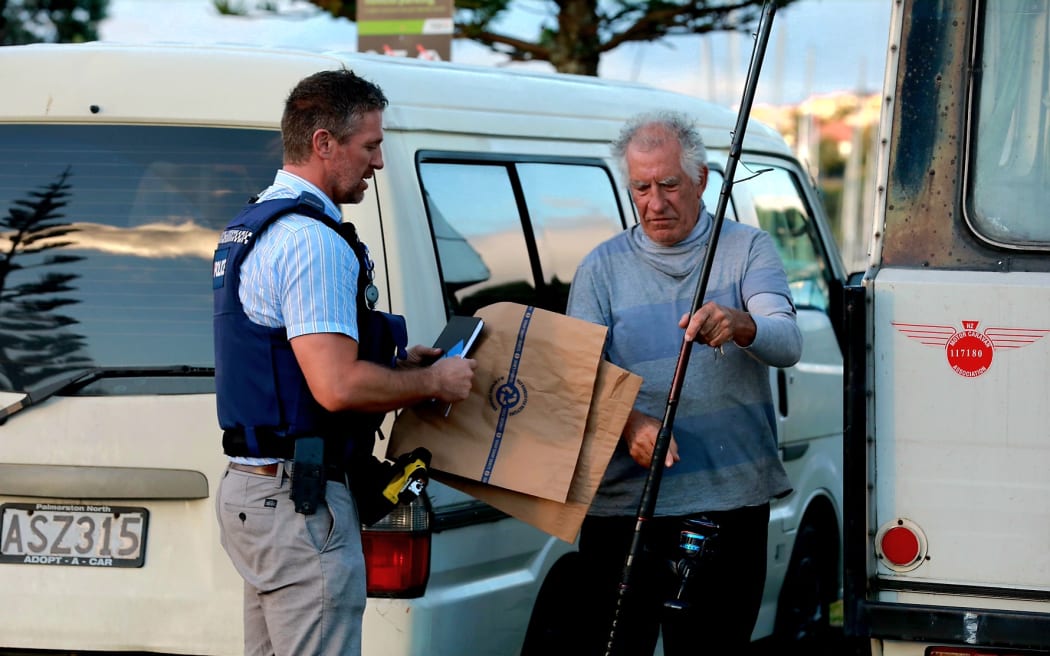Fisherman Paul Middleton hands over the fishing rod that snagged a body wrapped in rubbish bags from the water at Gulf Harbour on 12 March, 2024.