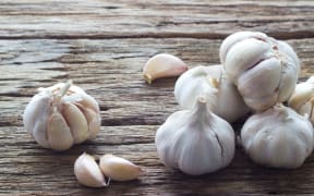 Garlic and garlic cloves on a wooden background.