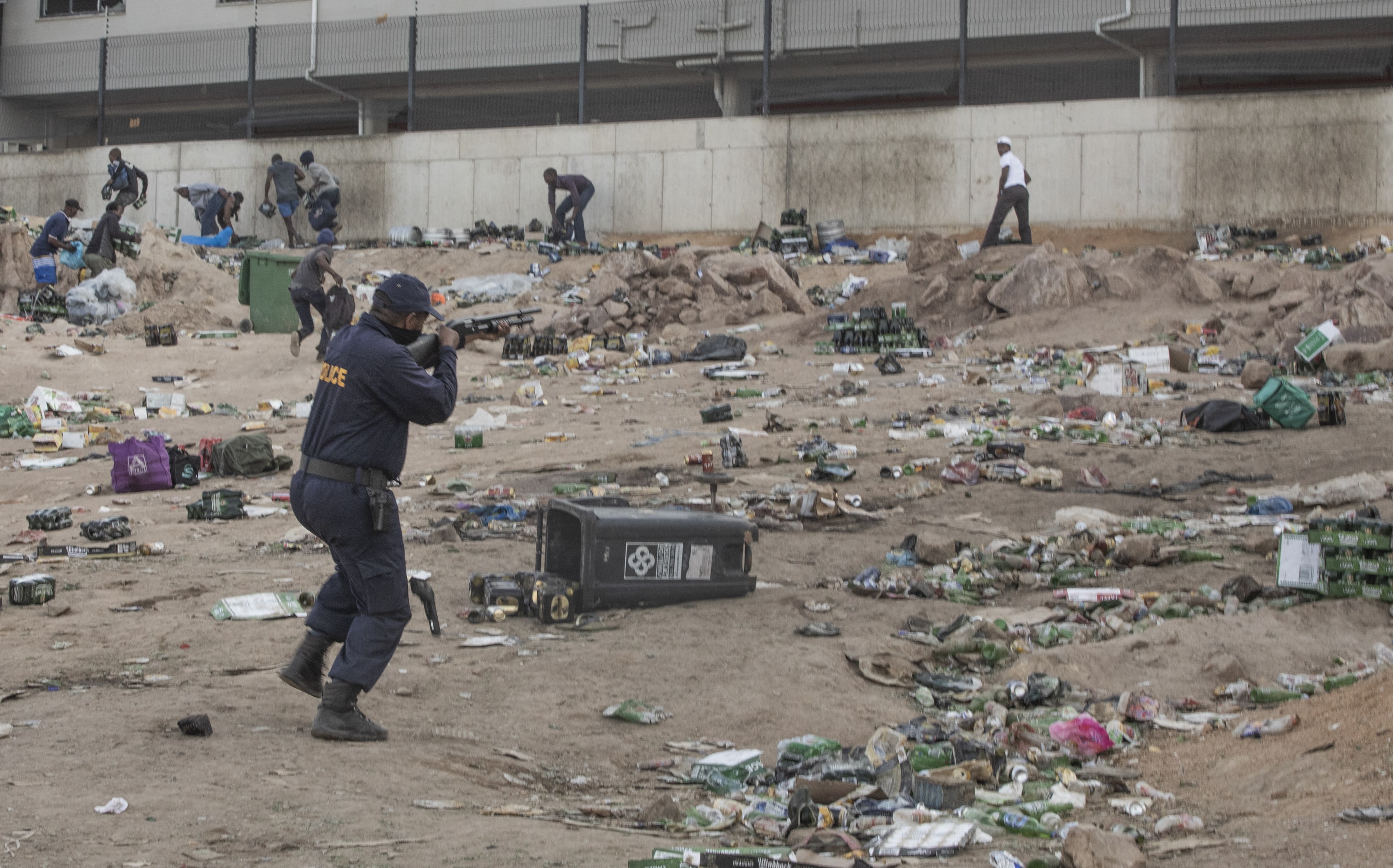 A member of SAPS shoots rubber bullets to disperse a crowd looting outside a warehouse storing alcohol in Durban on July 16, 2021,