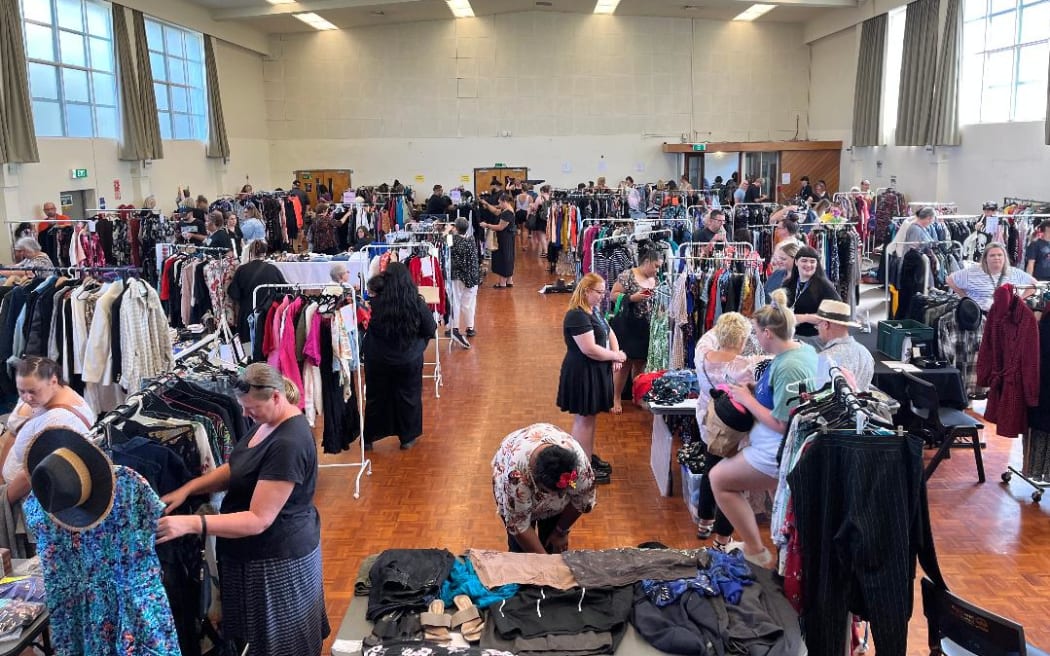 People shopping in a room filled with clothes on rails at Gently Loved's curvy market.