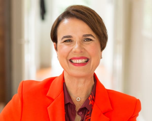 Galia BarHava smiles, wearing a bright orange suit.