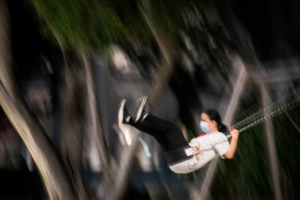 A woman in a mask plays on a swing in the Marina Bay area of Singapore on Saturday, 22 May 2021.