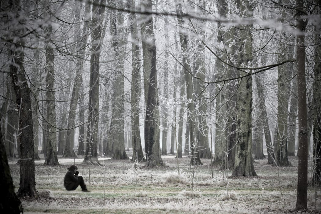 Woman seated alone in snowy forest