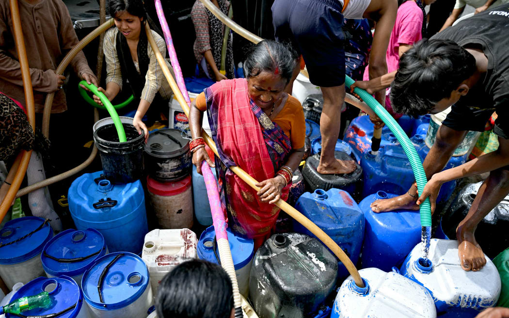 Residents fill their containers with water supplied by a municipal tanker in New Delhi on June 19, 2024 amid heatwave. Searing heatwave temperatures in northern India pushed power demand to a record high, the government said on June 18, with residents of the capital New Delhi also struggling with water shortages. (Photo by Money SHARMA / AFP)