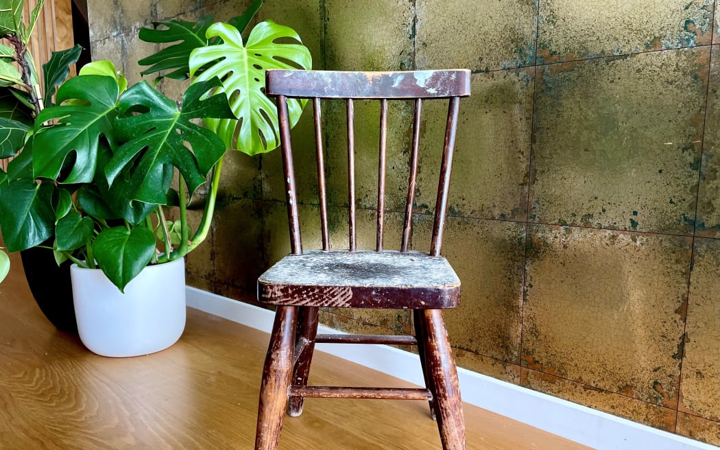 A little brown chair speckled with paint.