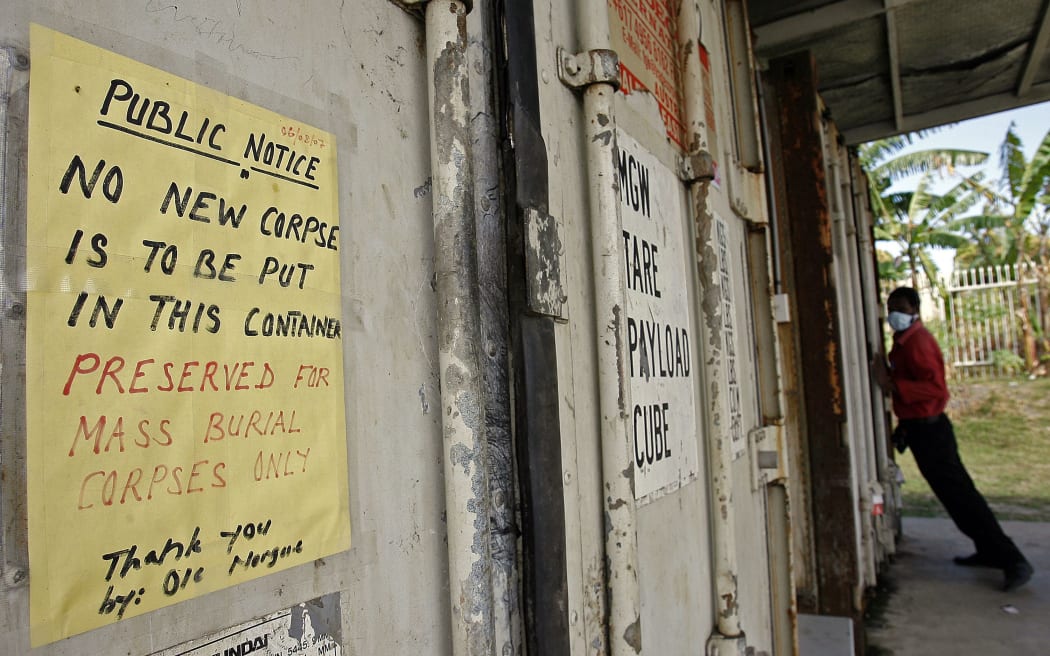 Morgue attendant Gideon Mati (R) struggles to close a refrigerated shipping container filled with unclaimed corpses behind Port Moresby General hospital, 2007.