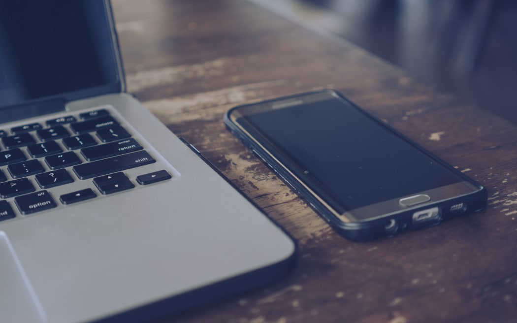 Laptop and smartphone on wooden table.