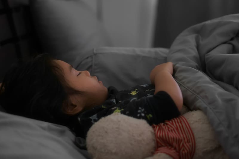 Child sleeping on grey dark bed