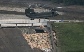 An RAF Chinook helicopter drops more bags of aggregate on the damaged section of spillway of the Toddbrook Reservoir dam above the town of Whaley Bridge in northern England on 4 August 2019.