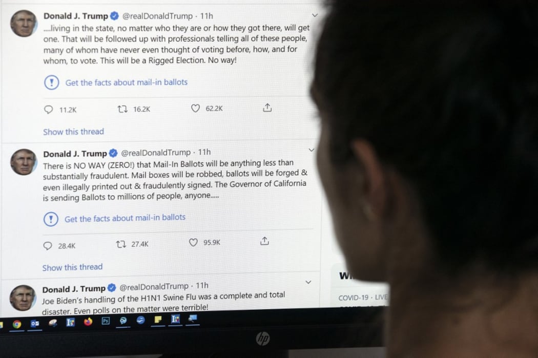 This illustration photo shows an editor in Los Angeles looking at the official Twitter account of US President Donald Trump on May 26, 2020, with two tweets by the president under which Twitter posted a link reading "Get the facts about mail-in ballots".