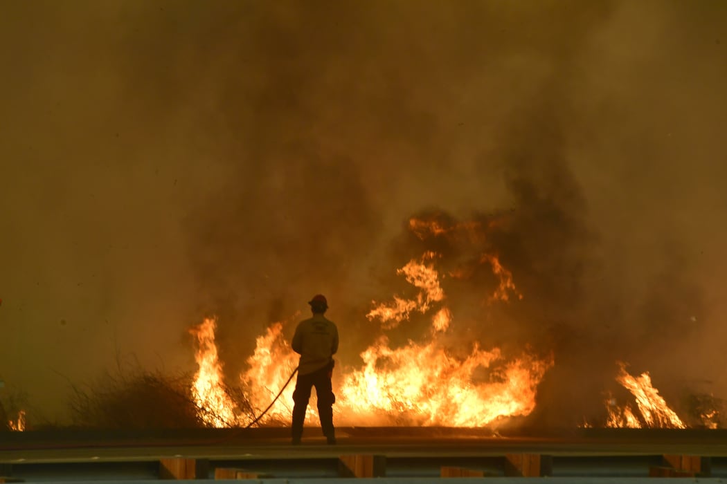 A firefighter battles flames near the US 101 highway in Ventura County.