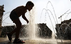 A young child refreshes himself with the waters of a fountain at Piazza Castello in Turin as they seek relief during a heatwave that continues to grip southern Europe.
