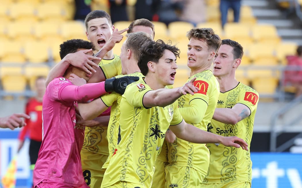 Wellington Phoenix players congratulate goalkeeper Alex Paulsen after his penalty save against Perth Glory.