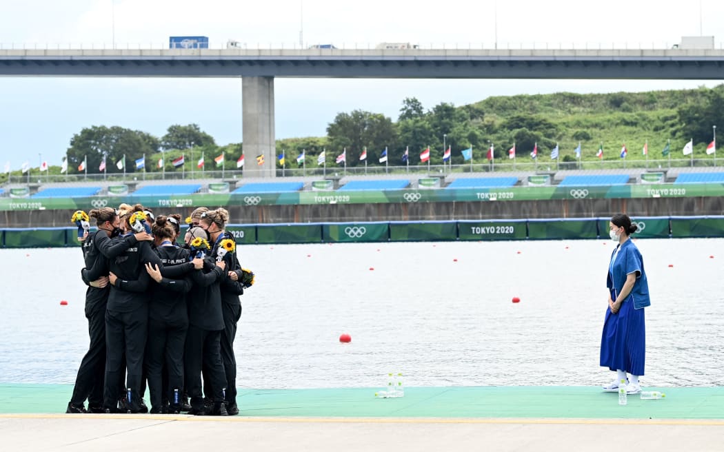 Silver medalists New Zealand's Ella Greenslade, Emma Dyke, Lucy Spoors, Kalsey Bevan, Grace Prendergast, Kerri Gowler, Beth Ross, Jackie Gowler and coxswain Caleb Shepherd hug on the podium following the women's eight final during the Tokyo 2020 Olympic Games.