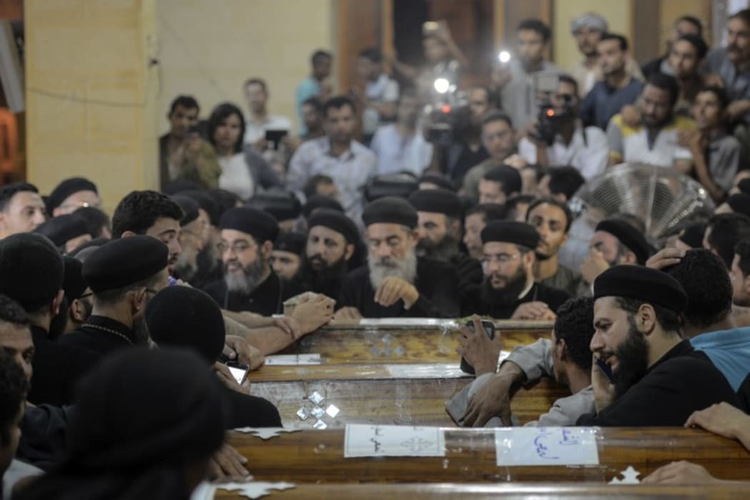 Relatives of killed Coptic Christians grieve by the coffins during the funeral at Abu Garnous Cathedral in the north Minya town of Maghagha