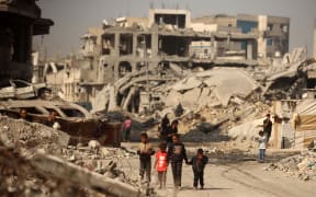 Palestinians walk amid the rubble of destroyed buildings in Gaza City, Palestine, on 5 November, 2025, during a ceasefire in the two-year-long Israel-Hamas war.
