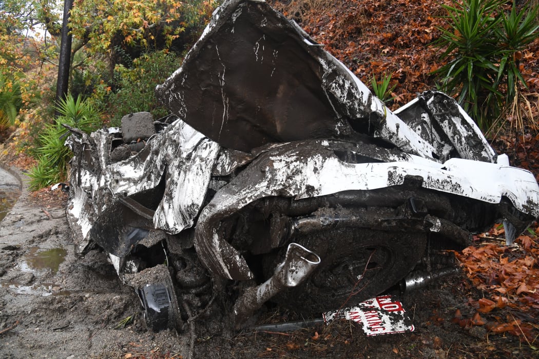 A car washed downhill in a rain-driven mudslide are seen in a neighborhood under mandatory evacuation in Burbank, California.