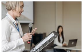 Woman holding microphone in front of a lectern