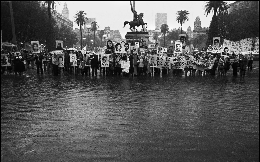 File: "Madres de Plaza de Mayo" remain upright on the flooded square in front of the Presidential Palace, claiming for their missing sons and daughters, circa 1982 in Buenos Aires.