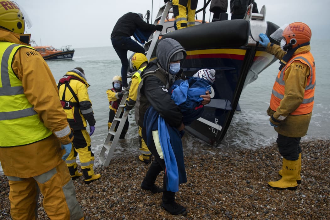 Migrants are helped ashore from a RNLI lifeboat at a beach in Dungeness, on the south-east coast of England.