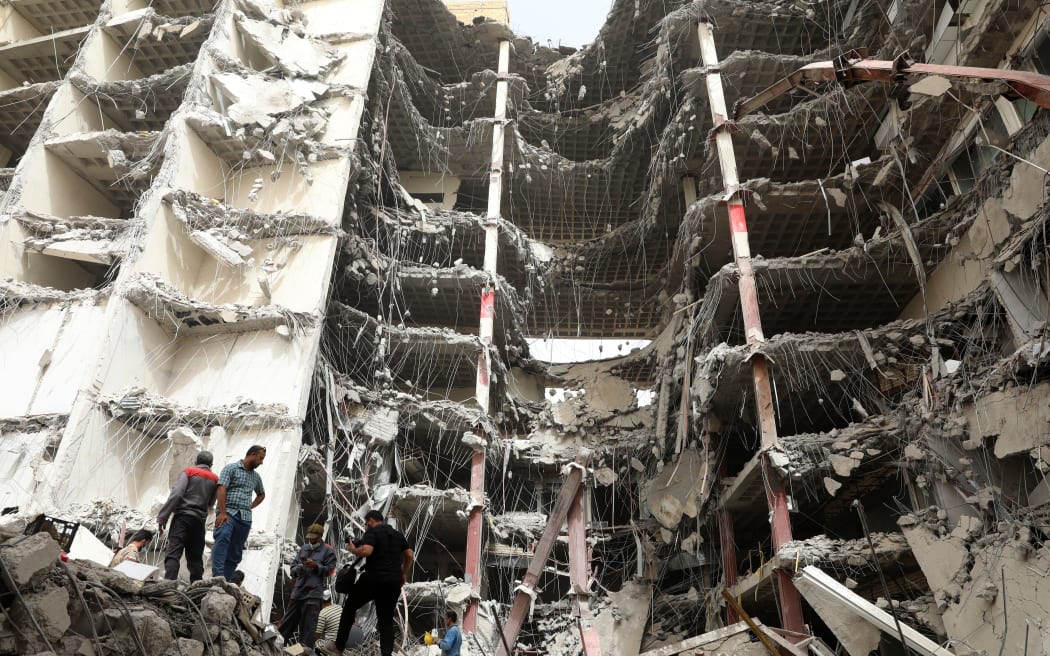 Iranians gather at the site where a 10-storey building collapsed as rescue operations continue in the southwestern city of Abadan.