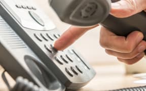 A close-up of a man's hand dialing numbers on a landline phone