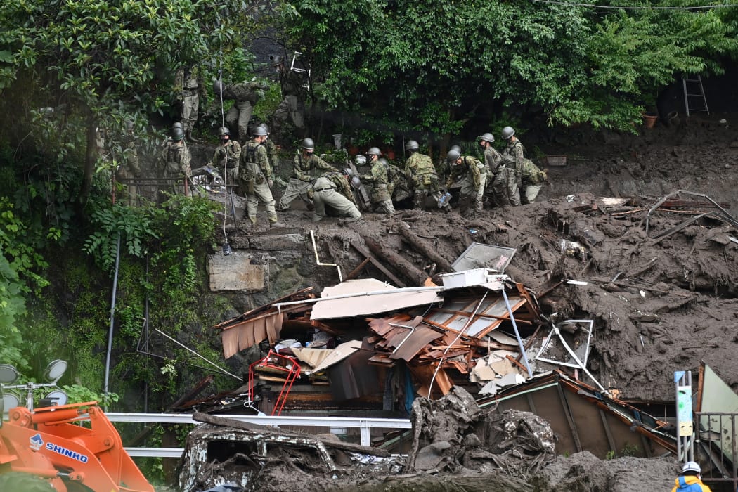 Members of Japan's Self-Defense Forces sift through mud and debris as they search for missing people at the scene of a landslide in Atami on 5 July, 2021.