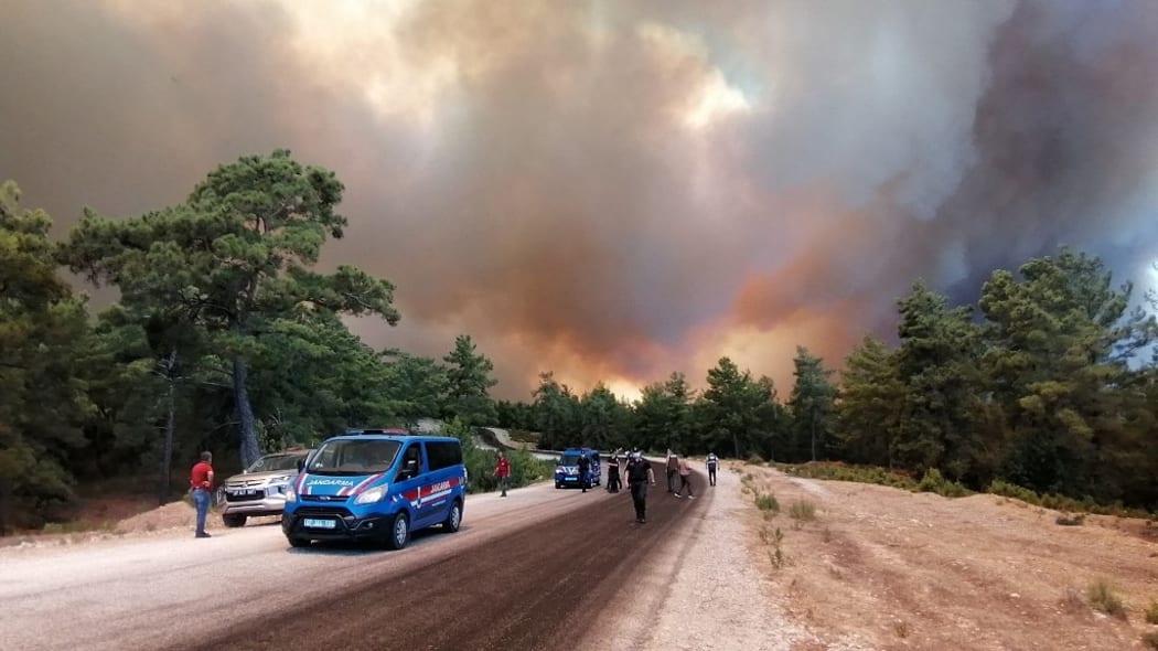 Flames and a massive cloud of smoke cover a fire-hit area in Manavgat, Antalya, southern Turkey, July 28, 2021. At least three people were killed, 100 injured and several have been evacuate in the massive wildfires of the resort city.