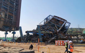 This handout photo taken on November 6, 2025 and released by the Ulsan Fire Department via Yonhap shows a 60 meter-high boiler tower (back C) at the Korea East-West Power Corporation after it collapsed in the southeastern city of Ulsan. At least seven people were trapped after a power plant structure collapsed on South Korea's east coast, the National Fire Agency said on November 6. (Photo by Handout / ULSAN FIRE DEPARTMENT / AFP) / - South Korea OUT / - SOUTH KOREA OUT /  - SOUTH KOREA OUT / RESTRICTED TO EDITORIAL USE - MANDATORY CREDIT "AFP PHOTO / ULSAN FIRE DEPARTMENT VIA YONHAP" - HANDOUT - NO MARKETING NO ADVERTISING CAMPAIGNS - DISTRIBUTED AS A SERVICE TO CLIENTS