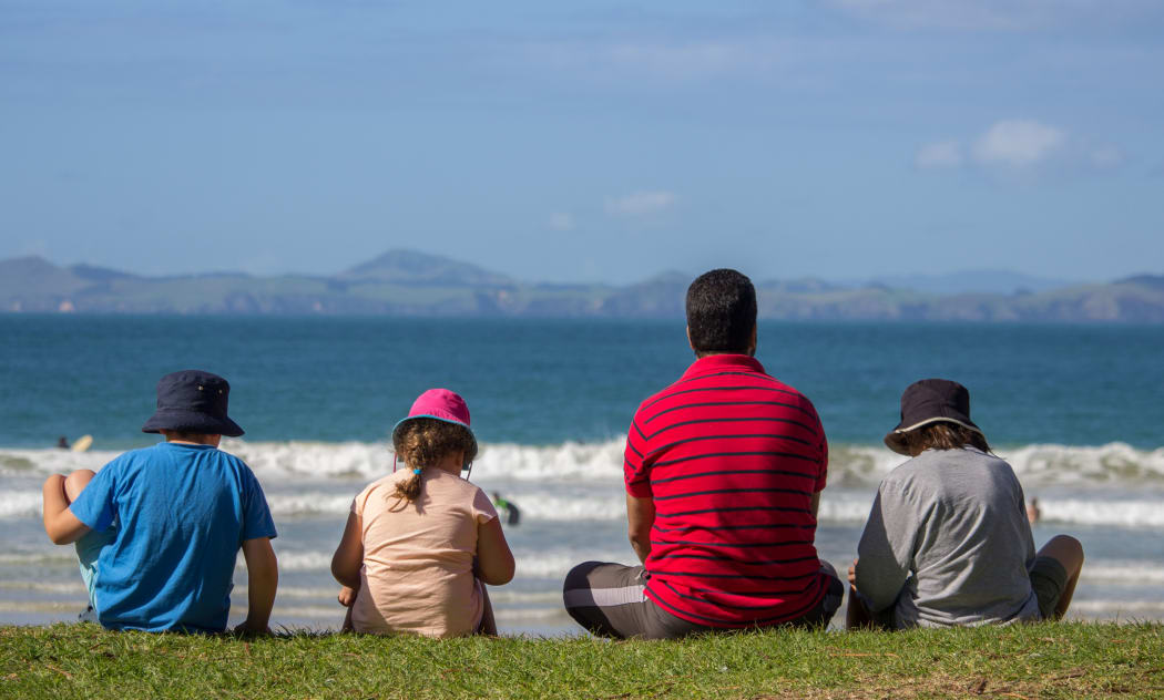 Father and Three Children Sitting at Matauri Bay Beach Northland New Zealand Watching the Waves