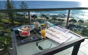 A table with newspaper and breakfast on it