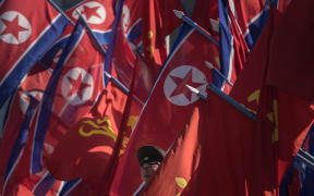 A Korean People's Army (KPA) soldier stands between flags prior to the opening ceremony for the Ryomyong Street housing development in Pyongyang on April 13, 2017.