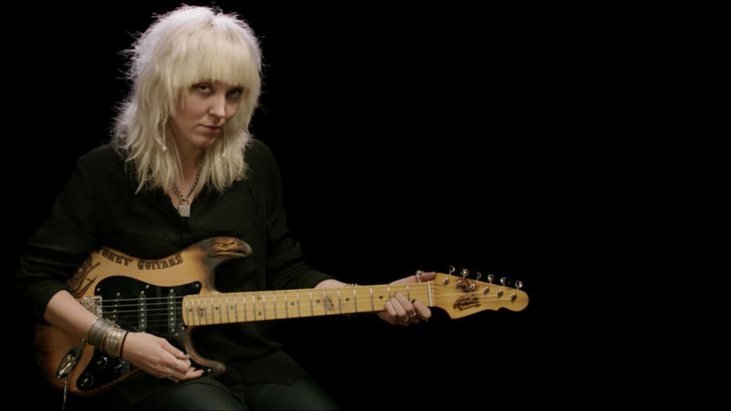 Cindy Hulej of Carmine Street Guitars holding a stratocaster style guitar