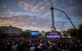 People gather at a fan zone on Place de la Bastille to watch a broadcast of the grand final of the Eurovision Song Contest 2025, which takes place in Basel, Switzerland, in Paris on May 17, 2025.