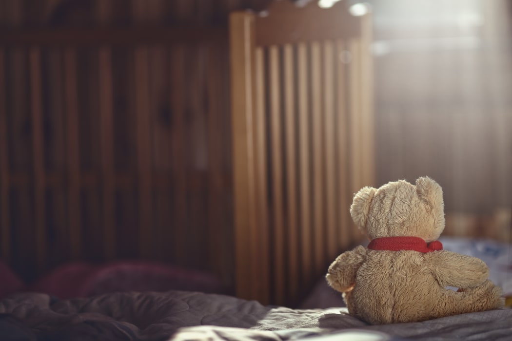 Teddy bear in an empty child's room.