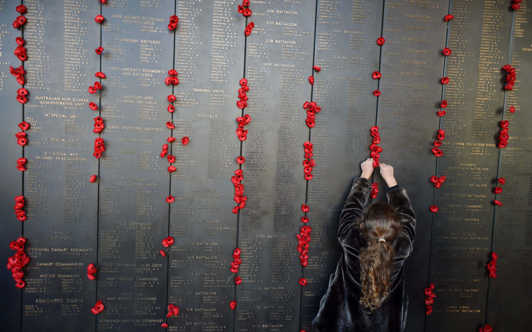 A girl places a poppy at the Roll of Honour at the Australian War Memorial after the ANZAC Day dawn service in Canberra, Saturday, April 25, 2015.