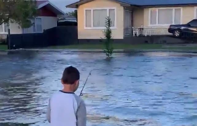 Jamie Lindsay's son fishing in their flooded street in Pirimai, Napier