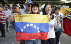Opposition activists celebrate outside polling stations after taking part in an opposition-organized vote to measure public support for Venezuelan President Nicolas Maduro's plan to rewrite the constitution.