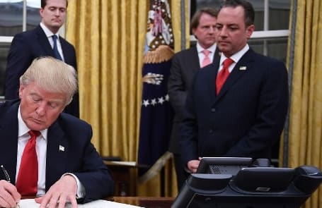 US President Donald Trump signs an executive order as Vice President Mike Pence and Chief of Staff Reince Priebus look on.