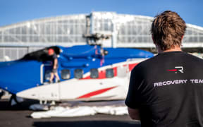 A Rocket Lab employee in front of a recovery helicopter