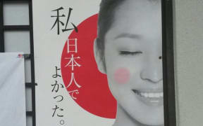 The poster, which has been put up in many places around Kyoto, says "I'm glad to be Japanese. Raise the Hinomaru (flag) with pride in your heart," - but the image used is of a Chinese model, and from a Beijing production company.